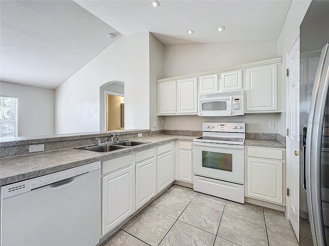 kitchen featuring lofted ceiling, sink, white cabinets, and white appliances