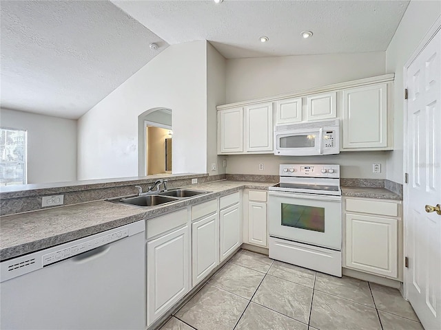 kitchen featuring vaulted ceiling, white cabinetry, sink, white appliances, and a textured ceiling