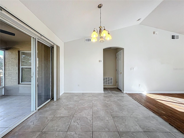 tiled spare room featuring vaulted ceiling and an inviting chandelier