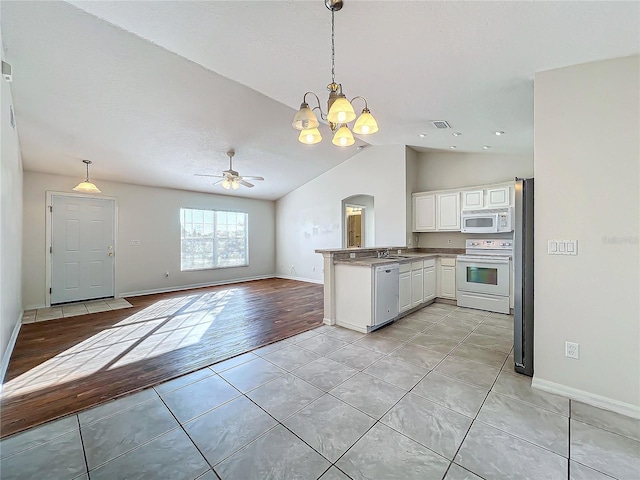 kitchen with light tile patterned flooring, decorative light fixtures, kitchen peninsula, white appliances, and white cabinets