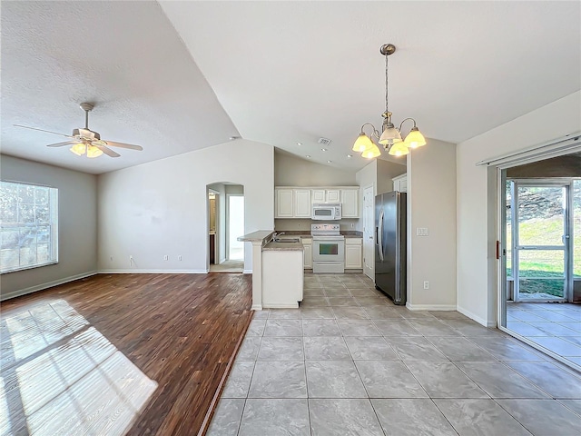 kitchen with lofted ceiling, sink, white cabinetry, range, and stainless steel fridge with ice dispenser