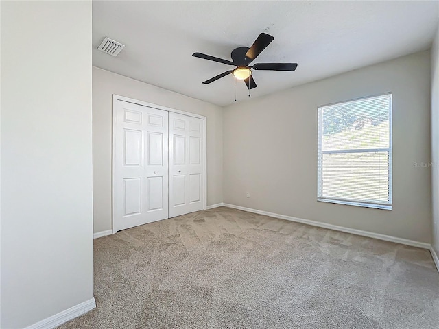 unfurnished bedroom featuring ceiling fan, a closet, and light carpet