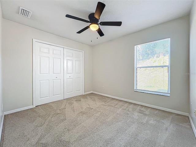 unfurnished bedroom featuring light colored carpet, ceiling fan, and a closet