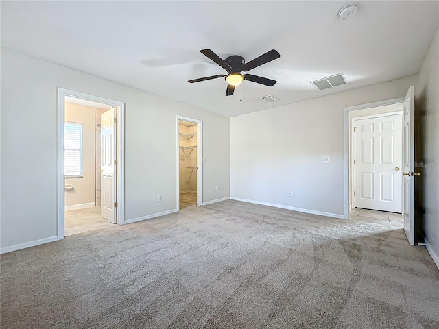 unfurnished bedroom with ensuite bathroom, light colored carpet, and ceiling fan