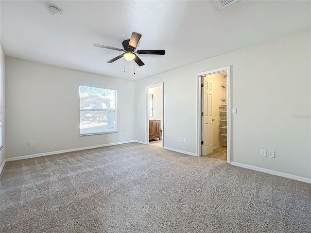 unfurnished bedroom with ceiling fan, ensuite bath, and light carpet