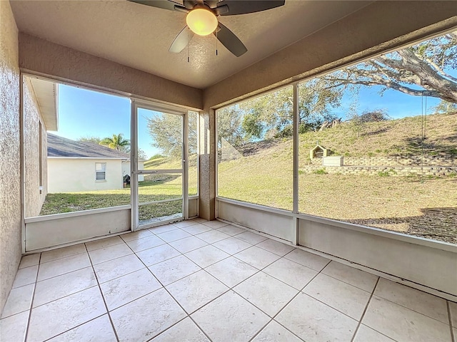 unfurnished sunroom with ceiling fan