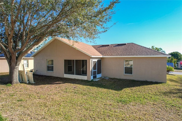 back of property with a sunroom and a lawn