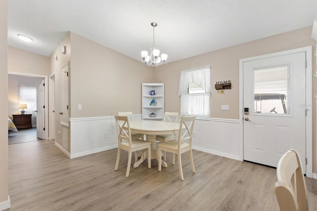 dining room featuring an inviting chandelier, a wealth of natural light, a textured ceiling, and light wood-type flooring