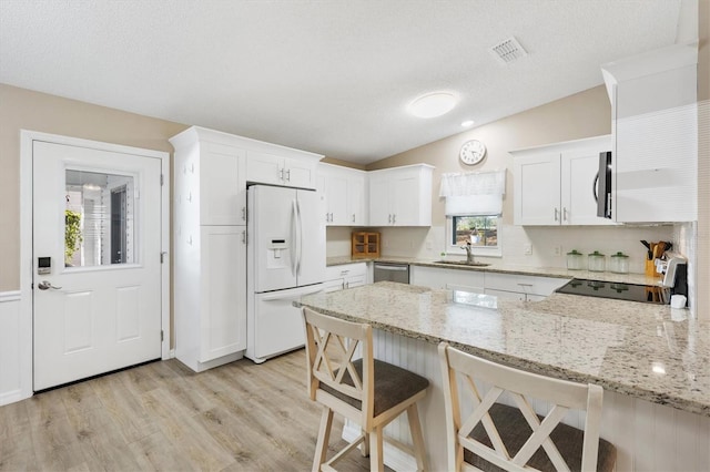 kitchen featuring white cabinetry, stainless steel appliances, light stone countertops, and sink