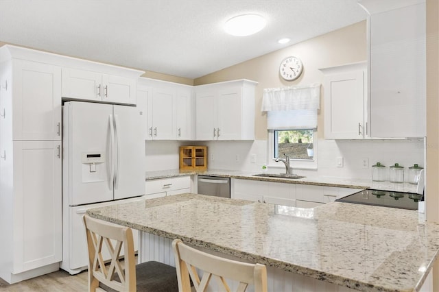 kitchen featuring white refrigerator with ice dispenser, sink, stainless steel dishwasher, and white cabinets