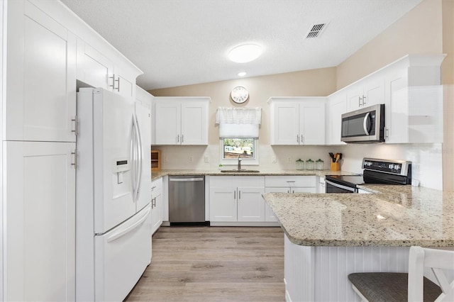 kitchen featuring appliances with stainless steel finishes, a breakfast bar, white cabinetry, sink, and kitchen peninsula