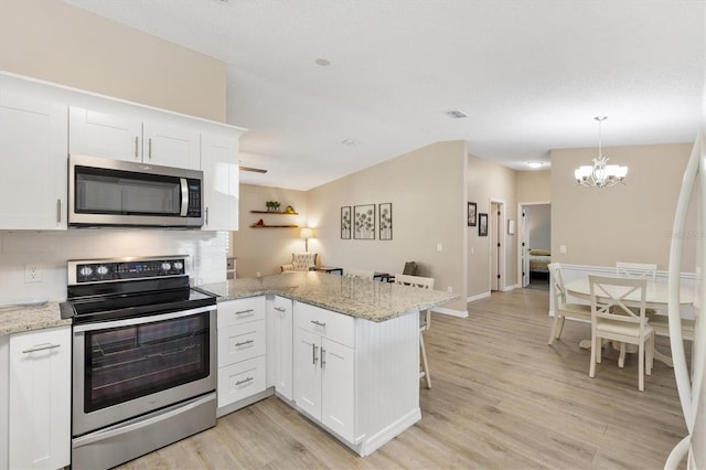 kitchen with white cabinets, light stone counters, kitchen peninsula, stainless steel appliances, and light wood-type flooring