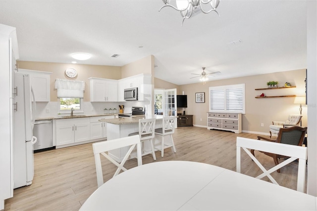 kitchen with sink, a center island, plenty of natural light, appliances with stainless steel finishes, and white cabinets