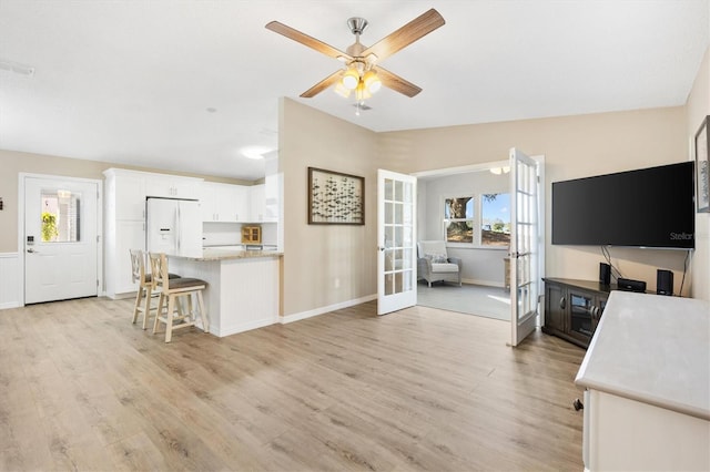 living room featuring lofted ceiling, light hardwood / wood-style flooring, french doors, and ceiling fan