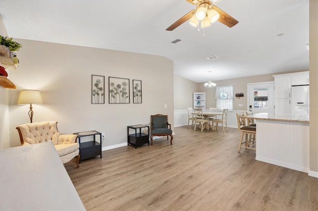 living room with lofted ceiling, ceiling fan with notable chandelier, and light hardwood / wood-style floors