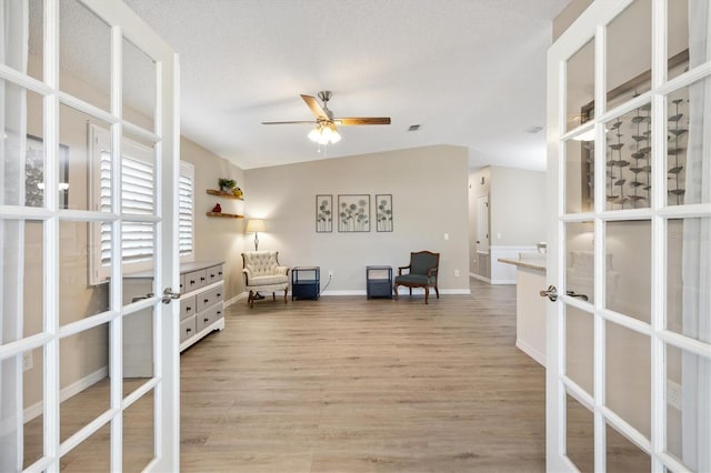 sitting room featuring french doors, lofted ceiling, a textured ceiling, ceiling fan, and light hardwood / wood-style floors