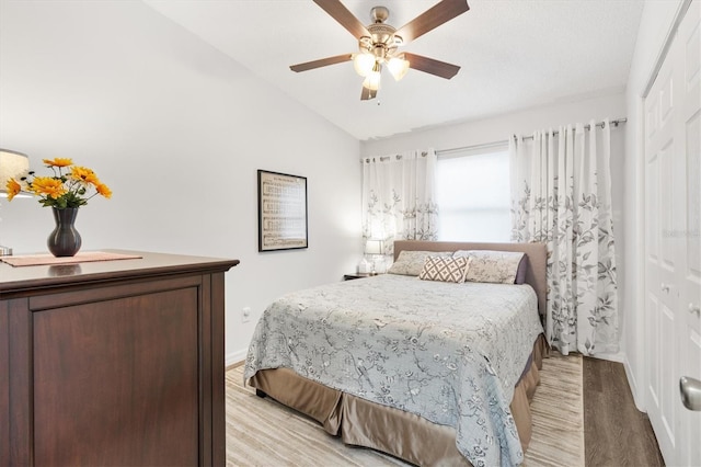 bedroom with ceiling fan, light hardwood / wood-style floors, vaulted ceiling, and a closet