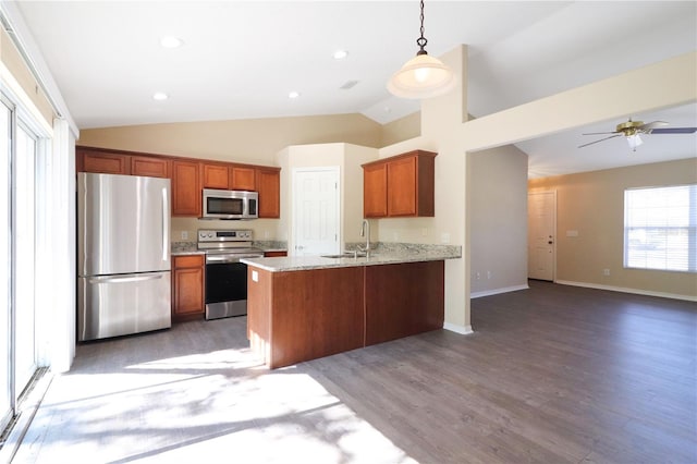 kitchen with sink, light stone counters, decorative light fixtures, appliances with stainless steel finishes, and kitchen peninsula