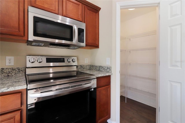 kitchen featuring light stone counters, stainless steel appliances, and dark hardwood / wood-style flooring