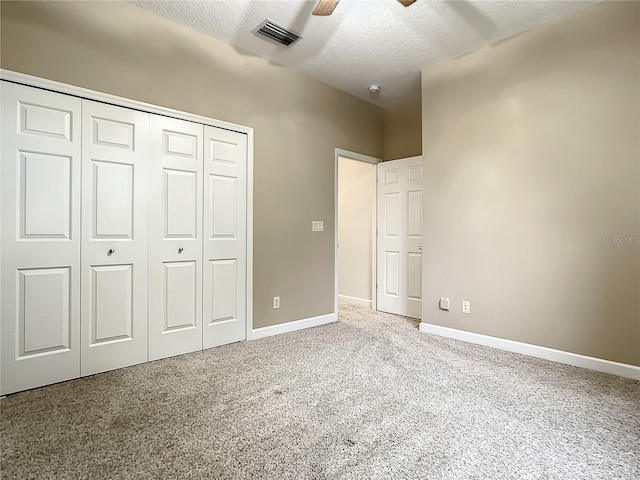 unfurnished bedroom featuring ceiling fan, light colored carpet, a closet, and a textured ceiling