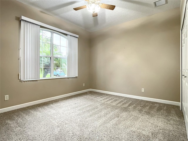 carpeted spare room featuring ceiling fan and a textured ceiling