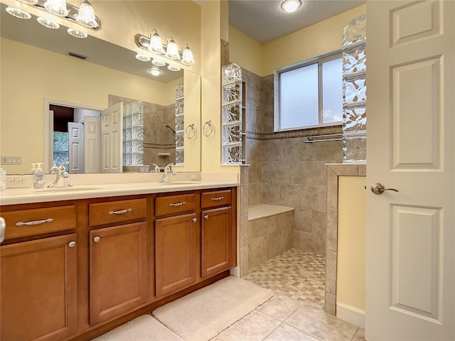 bathroom with tile patterned flooring, vanity, and tiled shower