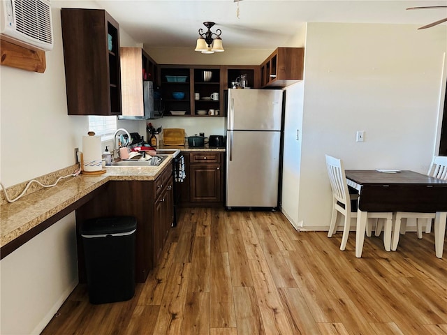 kitchen featuring sink, a wall mounted air conditioner, dark brown cabinets, stainless steel fridge, and light hardwood / wood-style floors