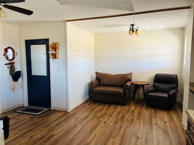 living area featuring ceiling fan, wooden walls, and light wood-type flooring