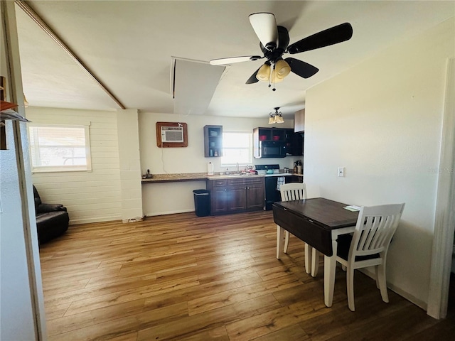 kitchen with sink, hardwood / wood-style flooring, ceiling fan, a wall unit AC, and range with electric stovetop