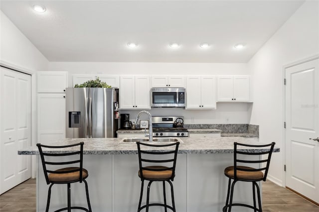 kitchen with white cabinetry, appliances with stainless steel finishes, a breakfast bar, and a center island with sink