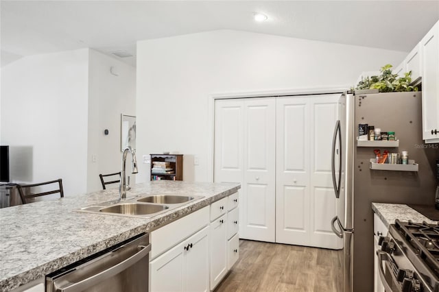 kitchen with sink, stainless steel appliances, light hardwood / wood-style floors, white cabinets, and vaulted ceiling