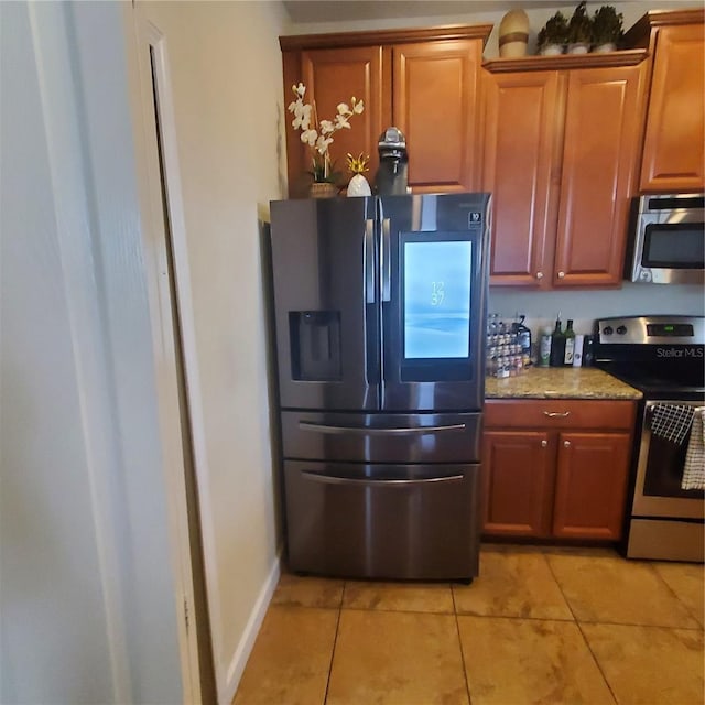 kitchen with light tile patterned floors, light stone countertops, and appliances with stainless steel finishes