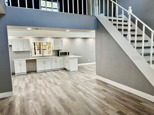 kitchen featuring sink, white cabinetry, built in desk, light hardwood / wood-style floors, and a high ceiling