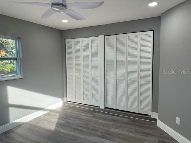 unfurnished bedroom featuring two closets, dark wood-type flooring, and ceiling fan