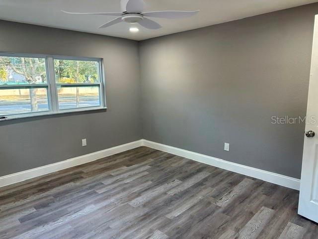 unfurnished room with dark wood-type flooring and ceiling fan