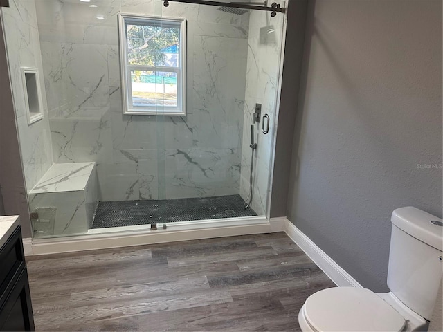 bathroom featuring vanity, hardwood / wood-style floors, a shower with shower door, and toilet