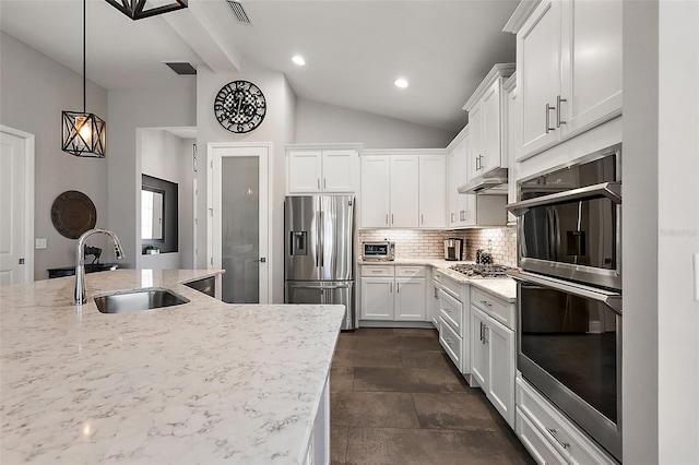 kitchen featuring appliances with stainless steel finishes, sink, white cabinets, backsplash, and hanging light fixtures