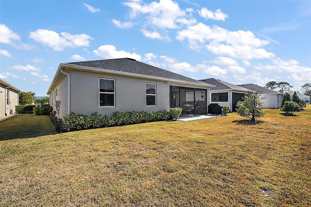 rear view of house featuring a sunroom and a lawn