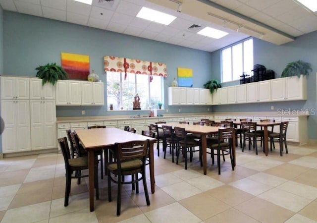 dining room with a high ceiling, rail lighting, and a drop ceiling