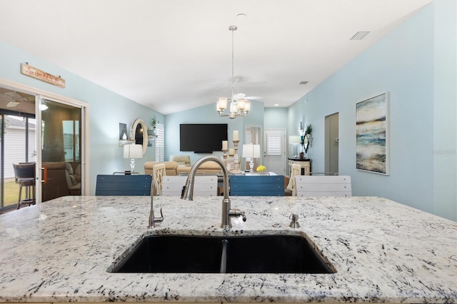 kitchen featuring sink, vaulted ceiling, light stone countertops, and hanging light fixtures