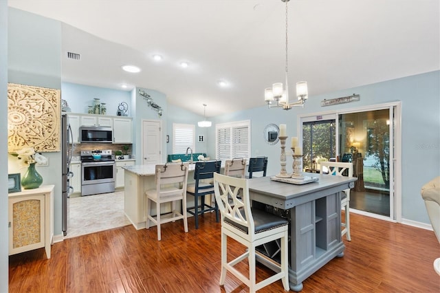 dining area with lofted ceiling, dark hardwood / wood-style floors, and an inviting chandelier