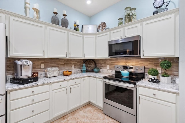 kitchen with white cabinetry, appliances with stainless steel finishes, light stone countertops, and backsplash