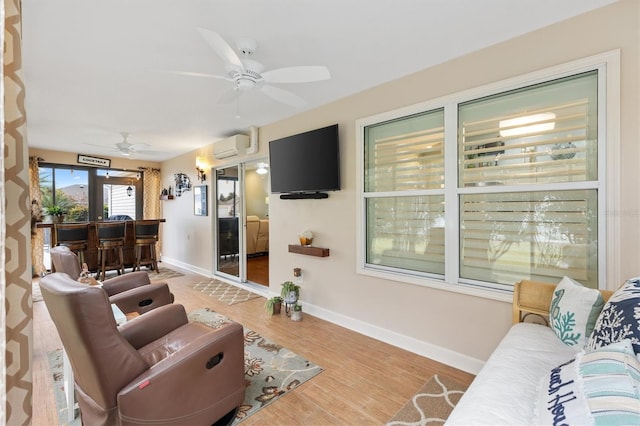 living room with ceiling fan, an AC wall unit, and light hardwood / wood-style floors