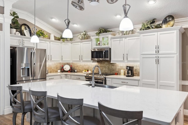 4515 Biggs Pl, The Villages, FL 32163 - kitchen featuring appliances with stainless steel finishes, light countertops, white cabinetry, backsplash, and a center island with sink