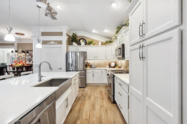4515 Biggs Pl, The Villages, FL 32163 - kitchen featuring appliances with stainless steel finishes, a sink, light wood-style floors, ornamental molding, and white cabinetry