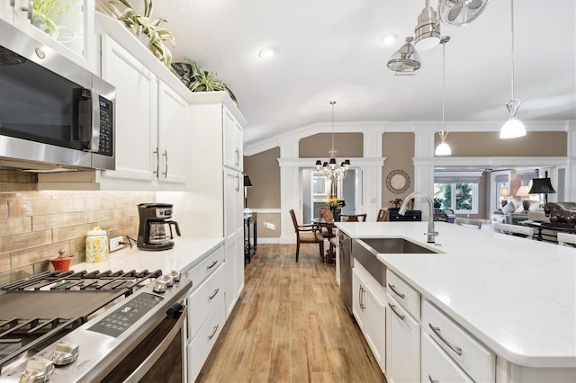 4515 Biggs Pl, The Villages, FL 32163 - kitchen with lofted ceiling, tasteful backsplash, a sink, appliances with stainless steel finishes, and a notable chandelier