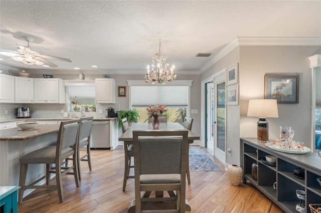 dining room featuring ceiling fan with notable chandelier, ornamental molding, light hardwood / wood-style floors, and a textured ceiling