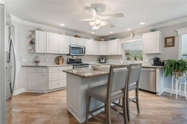 kitchen featuring a kitchen island, white cabinetry, appliances with stainless steel finishes, and light hardwood / wood-style flooring