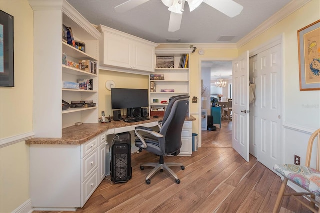 office space featuring built in desk, ornamental molding, light hardwood / wood-style floors, and ceiling fan