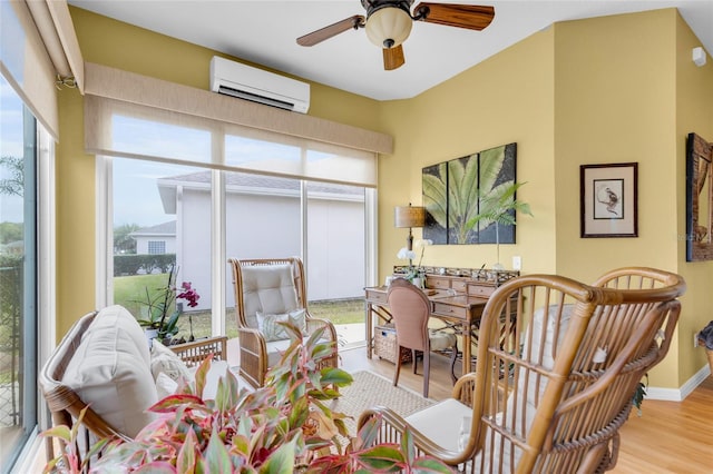 interior space featuring ceiling fan, an AC wall unit, baseboards, and light wood-style floors